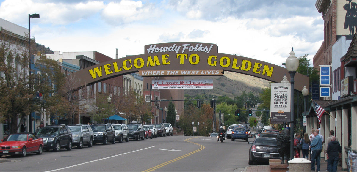 Welcome sign to Golden, Colorado with a street scene in the background.